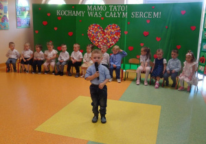 Chłopiec trzyma w ręku mikrofon, recytuje wiersz.